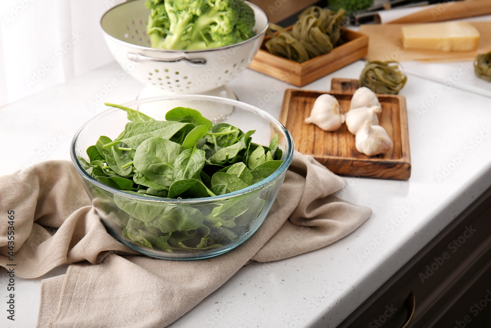 Bowl with fresh spinach on table in kitchen Bowl with fresh spinach on table in kitchen
