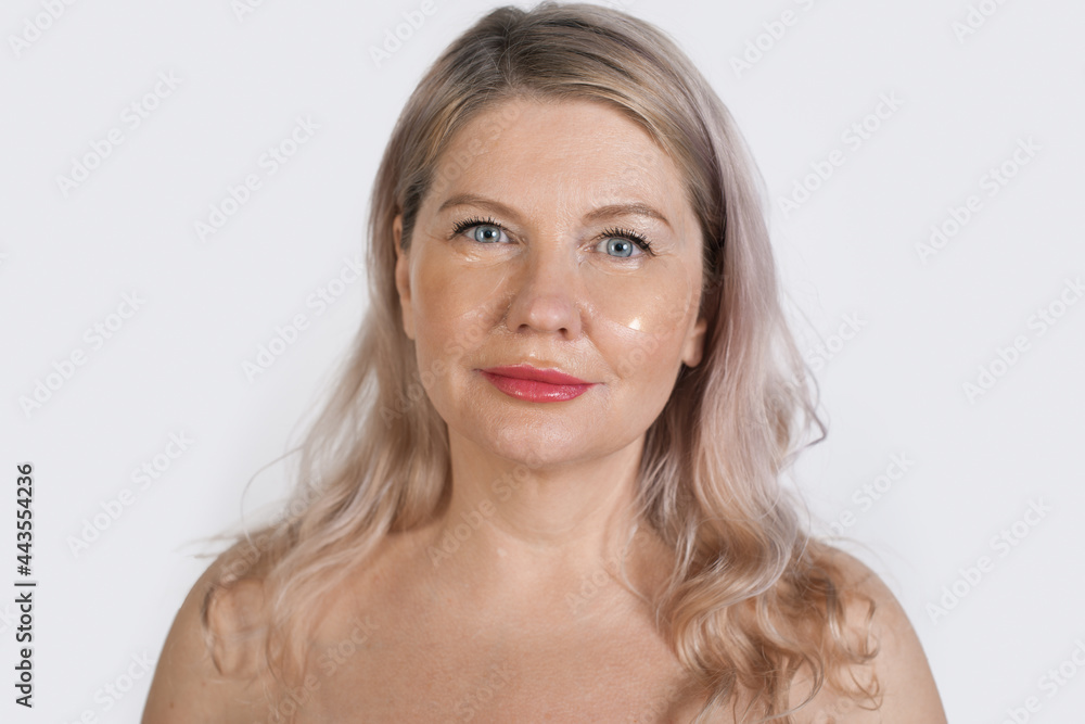 Senior blonde woman is wearing transparent eye patches posing at camera with bare shoulders Senior blonde woman is wearing transparent eye patches posing at camera with bare shoulders