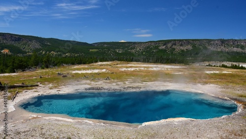 the deep blue gem pool hot spring in the cascade group on a sunny day in yellowstone national park, wyoming