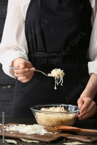 Woman preparing tasty sauerkraut at kitchen table, closeup