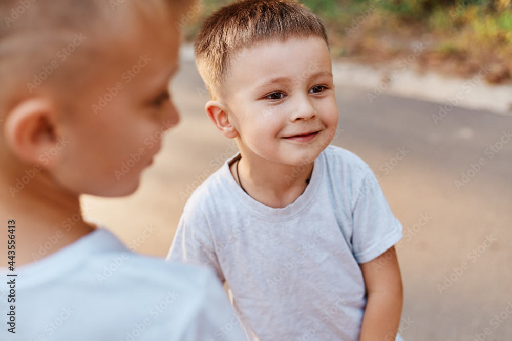 Portrait of two boys, siblings, brothers and best friends wearing white casual style t-shirts posing outdoors, spending free time together, children expressing happiness. Portrait of two boys, siblings, brothers and best friends wearing white casual style t-shirts posing outdoors, spending free time together, children expressing happiness.