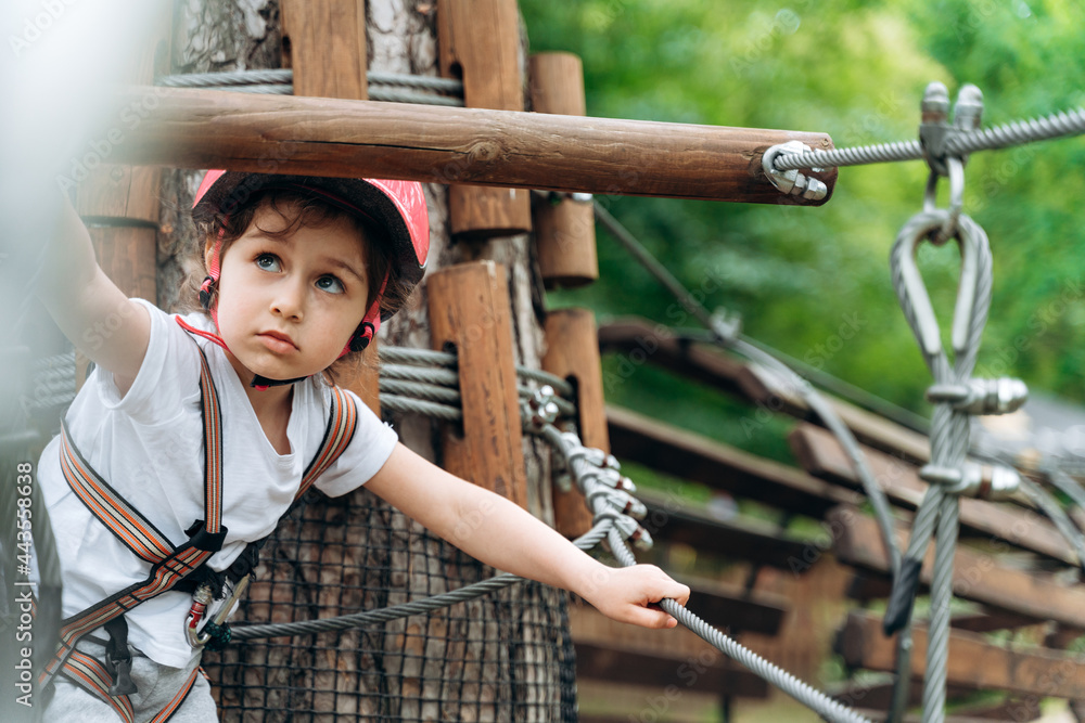 Beautiful, little girl in a protective helmet carefully passes obstacles. The child actively spends time Beautiful, little girl in a protective helmet carefully passes obstacles. The child actively spends time