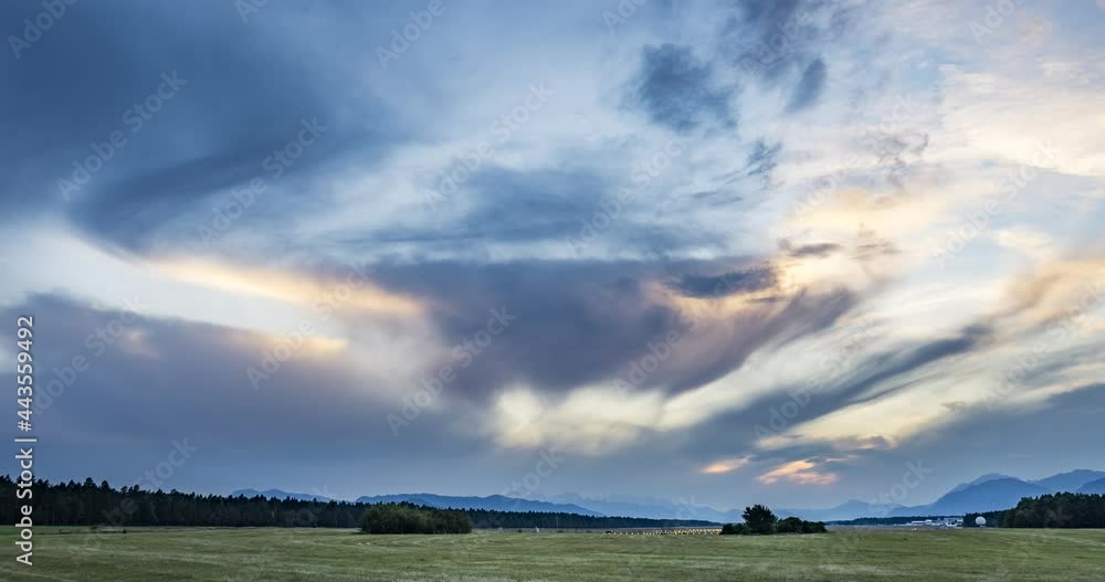Time lapse of dramatic sunset over farming field. Grassland farming field in the foreground and Alps in the distance. View of international airport in Slovenia. Zoom out, wide angle Time lapse of dramatic sunset over farming field. Grassland farming field in the foreground and Alps in the distance. View of international airport in Slovenia. Zoom out, wide angle