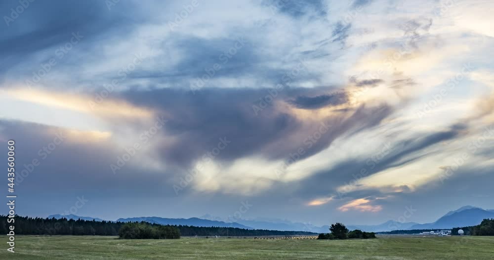 Time lapse of dramatic sunset over farming field. Grassland farming field in the foreground and Alps in the distance. View of international airport in Slovenia. Right tracking, wide angle Time lapse of dramatic sunset over farming field. Grassland farming field in the foreground and Alps in the distance. View of international airport in Slovenia. Right tracking, wide angle