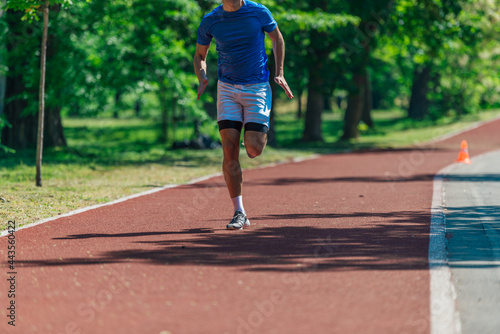 Photo of running shoes and strong athletic legs of sport man jogging on the running track