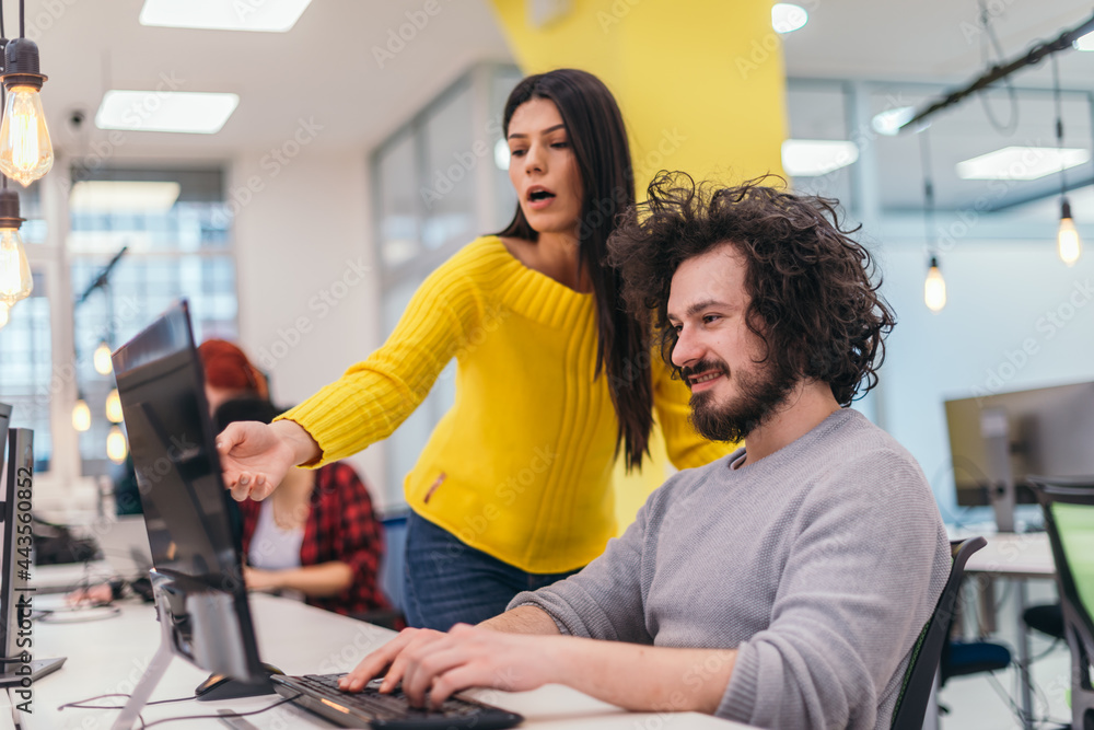 An attractive business girl standing next to a happy male colleague with clumsy hair and they are discussing new strategies in a modern office. An attractive business girl standing next to a happy male colleague with clumsy hair and they are discussing new strategies in a modern office.