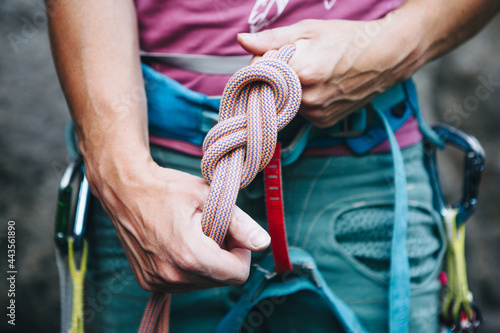 Foto Rock climber wearing safety harness making a eight rope knot