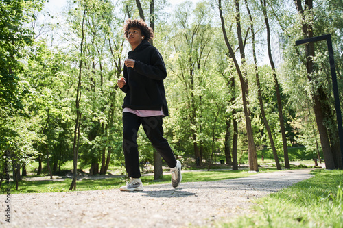 Male running in park and listening to music with concentration while jogging