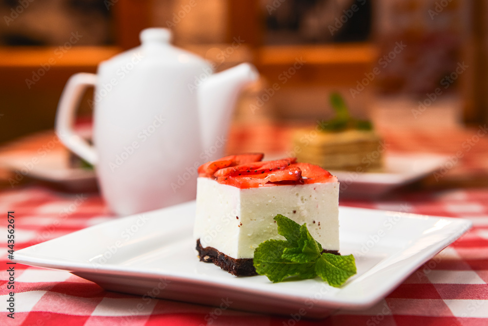 Strawberry cheesecake and fresh strawberries on top served on white plate on a rustic wooden table