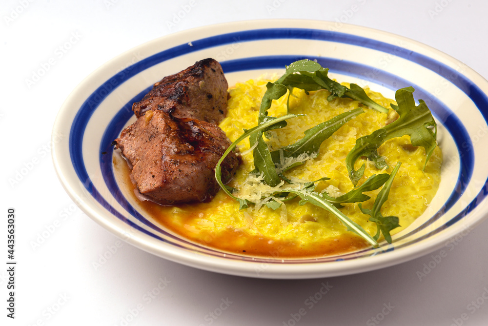 Risotto with meat steak and sauce served in a white plate over white backround. Risotto with meat steak and sauce served in a white plate over white backround.