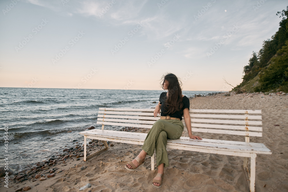 Attractive brunette sits on the sand beach. Concept of serenity at the beautiful place near the sea Attractive brunette sits on the sand beach. Concept of serenity at the beautiful place near the sea