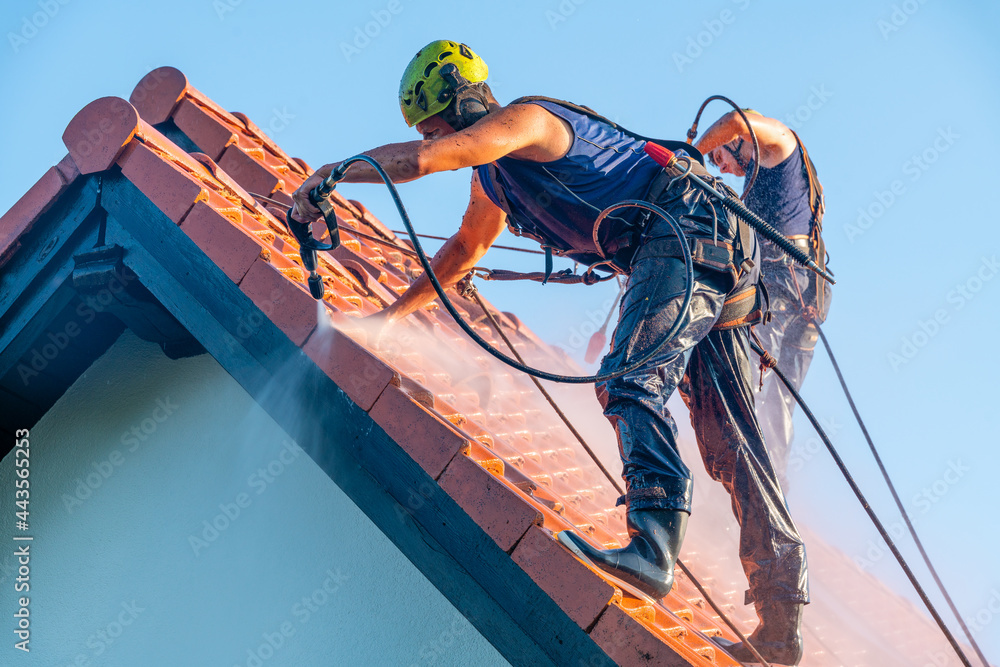 workers washing the roof with pressurized water