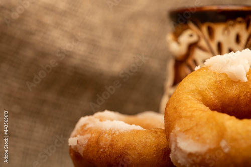 Fresh homemade doughnuts with powdered sugar and a earthenware mug of tea. Close-up Selective focus. photo