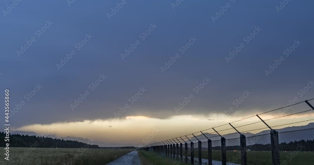 Time lapse of storm clouds forming in the evening. Slovenia international airport fence. Gravel or dirt road close to agricultural fields. Right tracking, wide angle