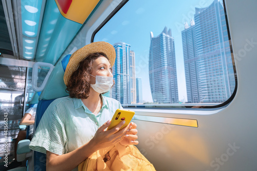Photography Woman in a protective medical mask rides the subway, holds a smartphone in her h