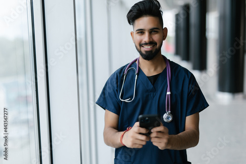 Young male doctor sit at desk in hospital consult client on modern smartphone online