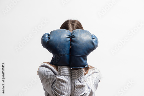 Fototapeta Naklejka Na Ścianę i Meble -  Woman close her face by the boxing gloves close up on the white background.