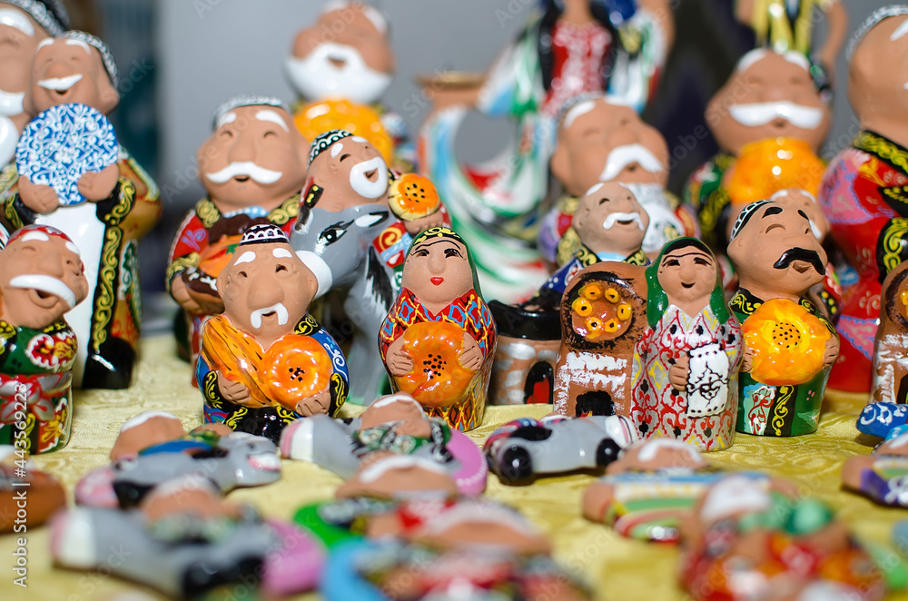 Traditional ceramic figurines of happy Uzbek men and women in national clothes with bread in hands