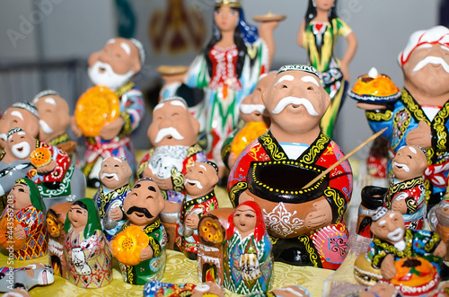 Traditional ceramic figurines of happy Uzbek men and women in national clothes with bread in hands