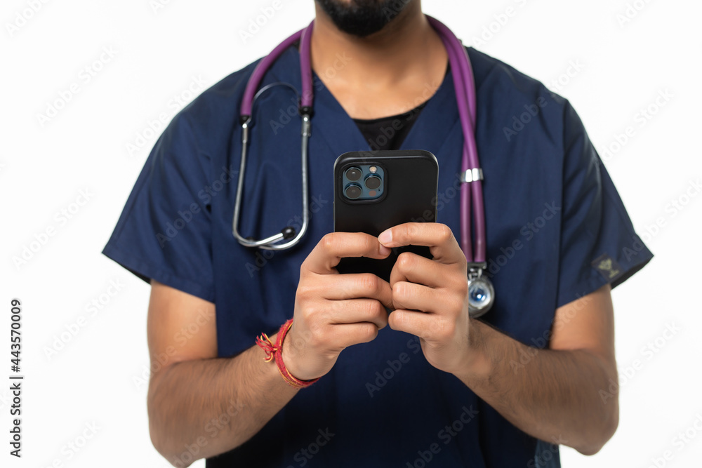 Indian man doctor standing isolated on white background looking attentively at screen of cellphone Indian man doctor standing isolated on white background looking attentively at screen of cellphone