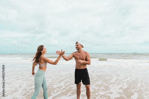 Man and woman give high five after the workout training at the beach.