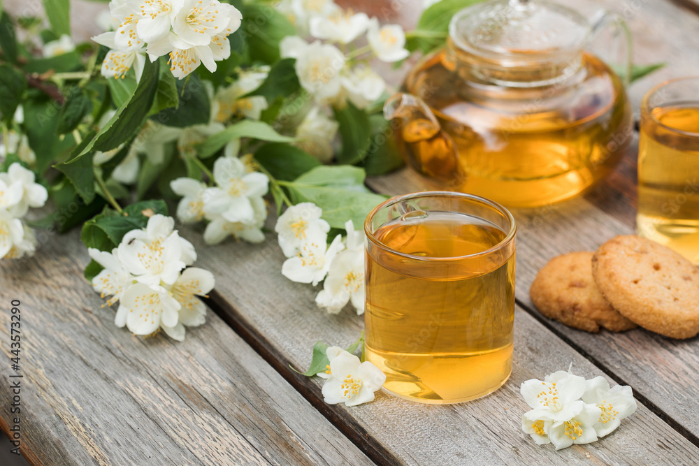 Green Chinese tea with jasmine in mugs and a teapot on a wooden table top with a bouquet of jasmine flowers. Green Chinese tea with jasmine in mugs and a teapot on a wooden table top with a bouquet of jasmine flowers.