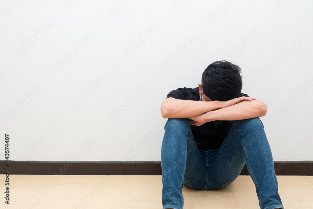 Man sit against the wall put head down feeling strain and sad emotion Man sit against the wall put head down feeling strain and sad emotion