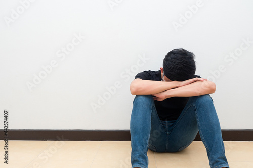 Man sit against the wall put head down feeling strain and sad emotion
