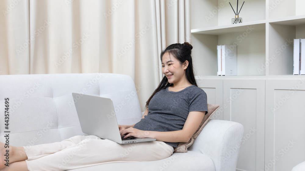 Asian woman sitting on sofa and using laptop to shop online with credit card to register for payment or online transactions, Financial transactions and Internet security, Shopping with credit card. Asian woman sitting on sofa and using laptop to shop online with credit card to register for payment or online transactions, Financial transactions and Internet security, Shopping with credit card.