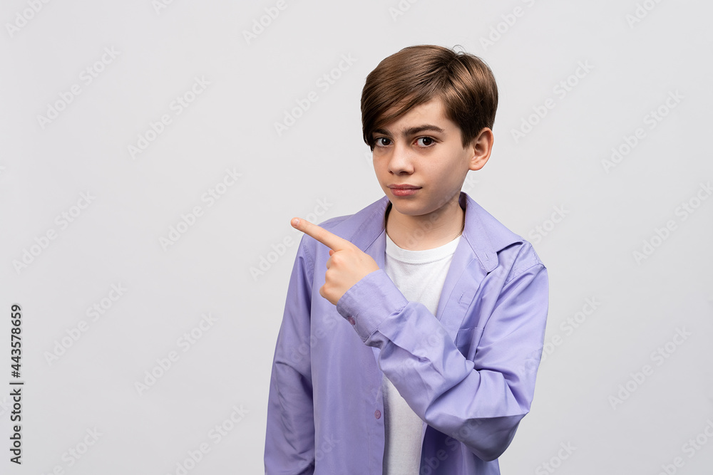 Handsome boy looking at the camera and showing aside on copyspace. Pay attention to important information Handsome boy looking at the camera and showing aside on copyspace. Pay attention to important information