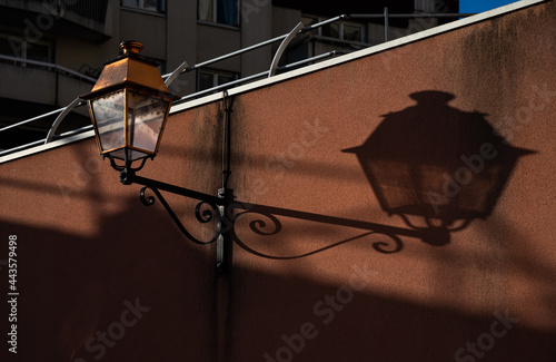 Retro style lantern and its shadow on the wall in Parisian suburb. France. Abstract composition. Differance in similarity concept. photo