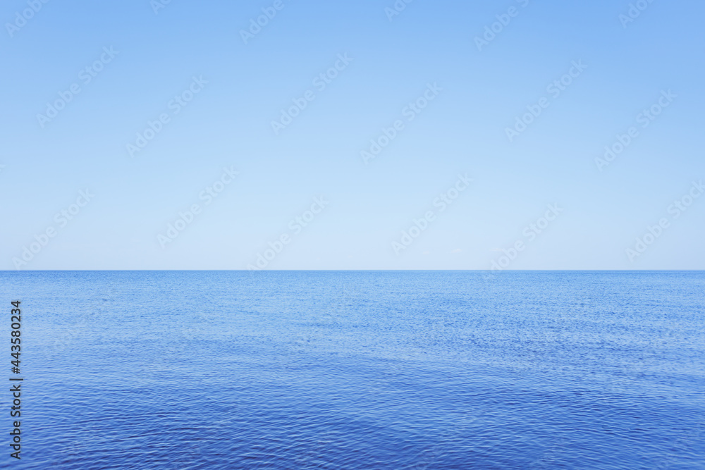 Obraz premium a calm blue lake against a clear sky with a horizon and a space for text.