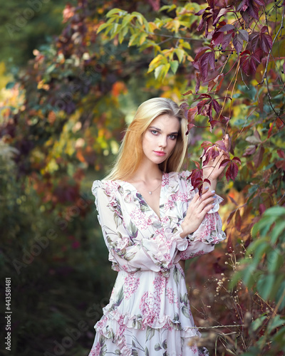 Blonde in the forest with a vine in a pink dress