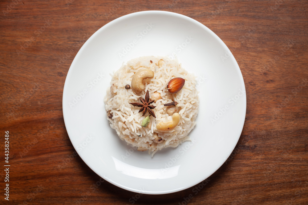 Indian Basmati Rice or Kasmiri pulao (pulav) or Dry Fruits Pulao garnished with dry fruits and spices in a black bowl