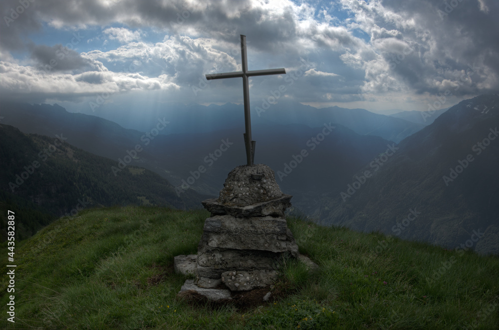 Silhouette of cross on mountain in Italian alps under dramatic sky