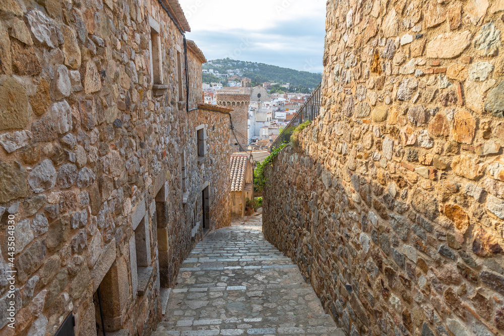 Narrow street with stone walls and floor of an old village in Tossa de Mar. Narrow street with stone walls and floor of an old village in Tossa de Mar.