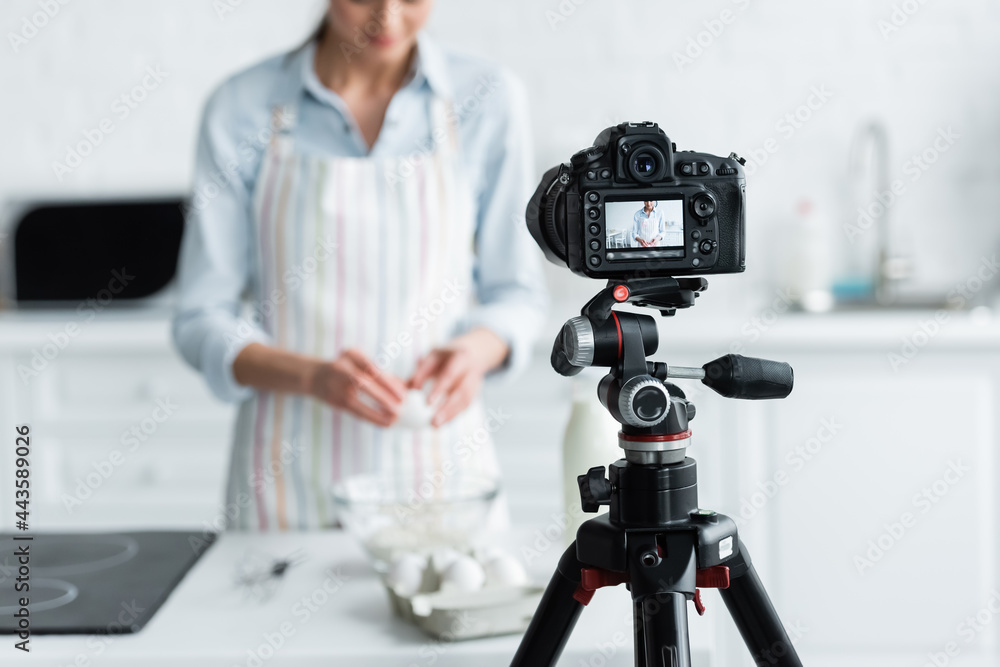 selective focus of digital camera near cropped culinary blogger during online cooking.