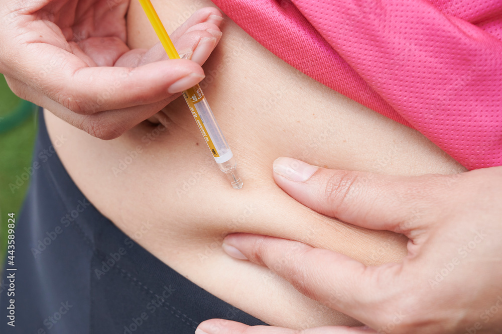 Woman is doing an heparin injection in her abdomen at home Woman is doing an heparin injection in her abdomen at home