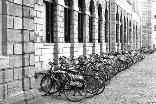 Vélos alignés à Dublin en Irlande le long d'un bâtiment ancien en pierre.  Cliché en noir et blanc 
