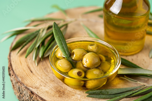 Virgin olive oil bottle and green olives on wooden table photo