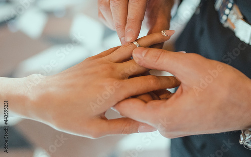 Closeup of putting a wedding ring onto the bride finger. Couple exchanging wedding rings. High quality photo