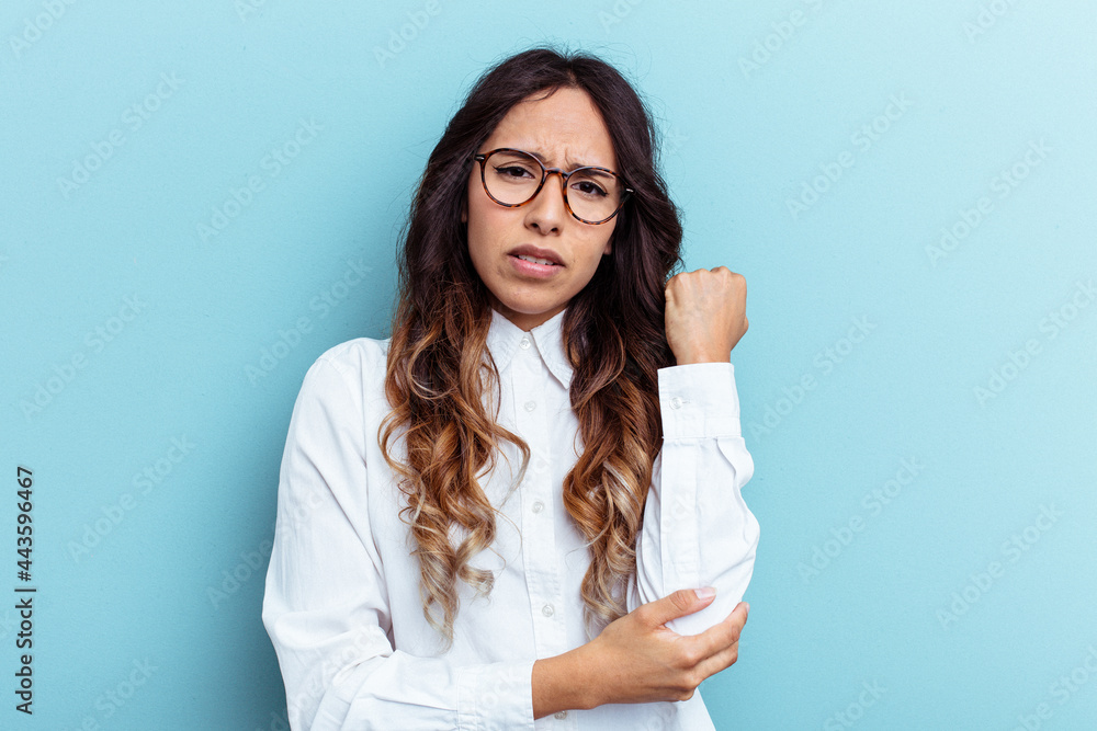 Young mexican woman isolated on blue background massaging elbow, suffering after a bad movement. Young mexican woman isolated on blue background massaging elbow, suffering after a bad movement.