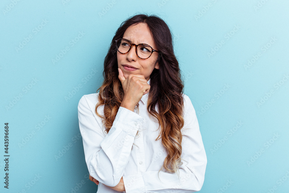 Young mexican woman isolated on blue background looking sideways with doubtful and skeptical expression. Young mexican woman isolated on blue background looking sideways with doubtful and skeptical expression.