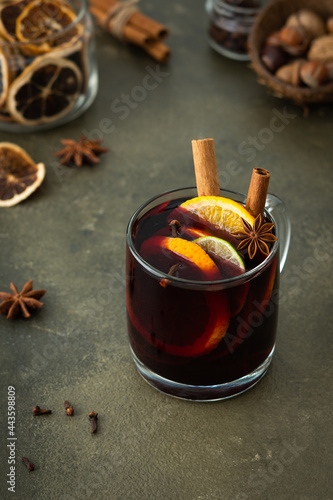 Mulled wine with lime and orange slices, cinnamon and cloves, hot winter drink in a glass mug
