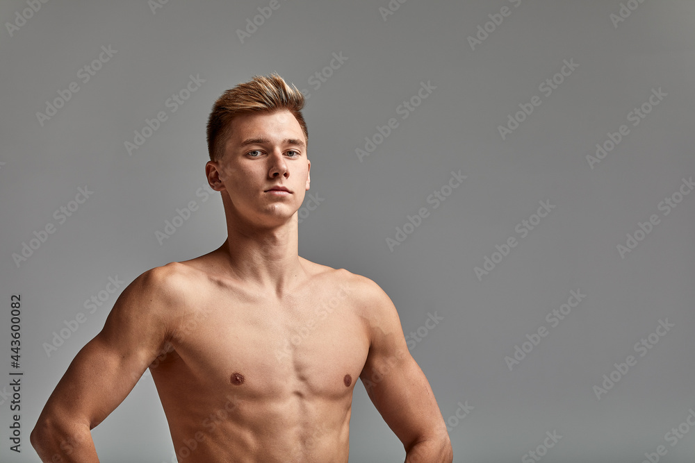 Swimmer on a gray background, hands on the belt, copy space, gray background, young swimmer with a perfect body.