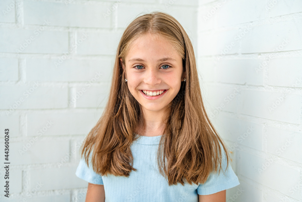 Portrait of a beautiful smiling little teenage girl against a white brick wall Portrait of a beautiful smiling little teenage girl against a white brick wall