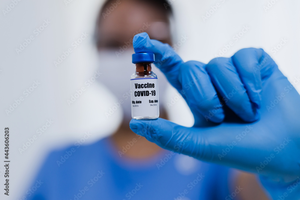 Doctor working had in gloves holding bottle of vaccine, Covid-19 or coronavirus vaccine