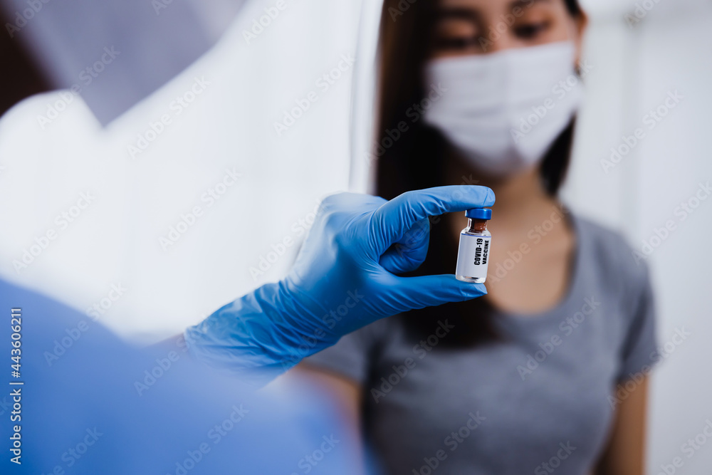 Doctor working had in gloves holding bottle of vaccine explain and prepare making injection to Asian woman patient in medical mask background, Covid-19 or coronavirus vaccine Doctor working had in gloves holding bottle of vaccine explain and prepare making injection to Asian woman patient in medical mask background, Covid-19 or coronavirus vaccine