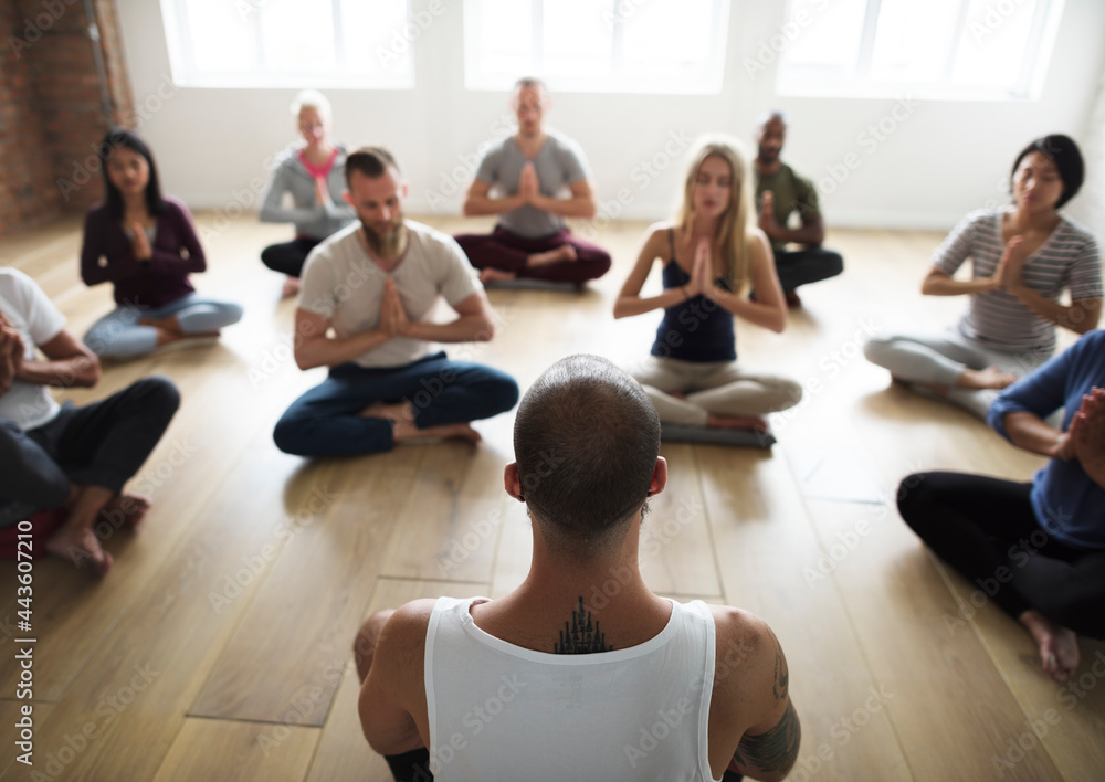 Diverse group of people in a yoga class doing a meditating pose