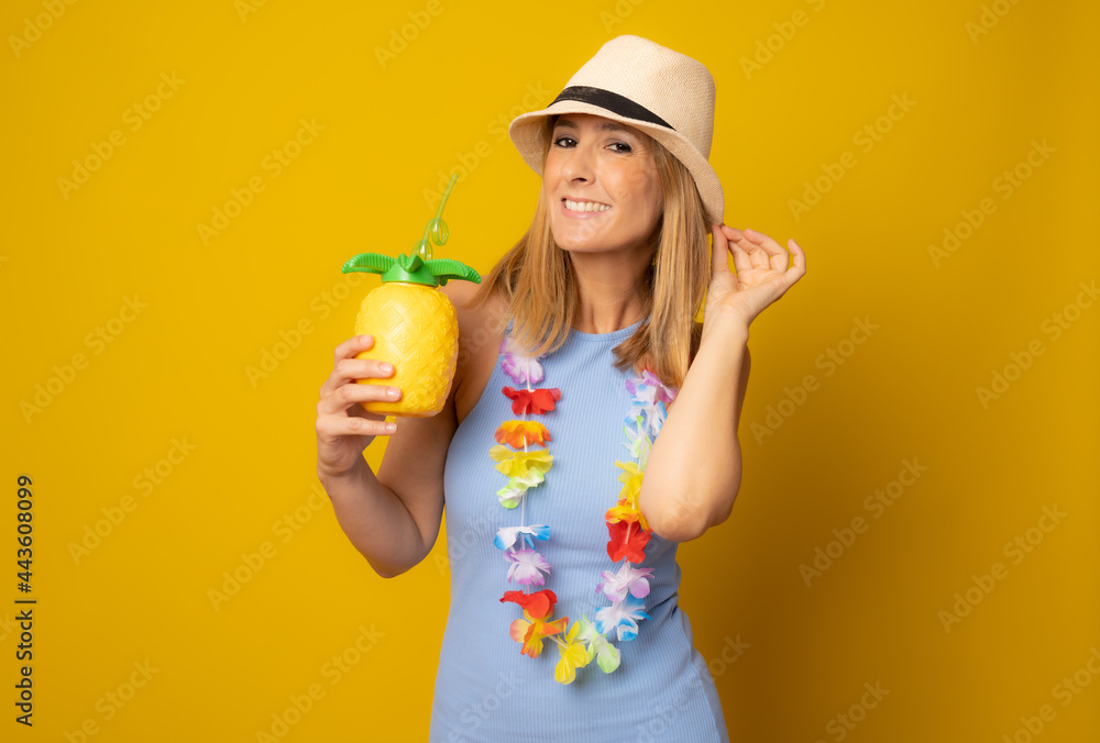 Cheerful beautiful young woman in hat drinking cocktail with straw over yellow background Cheerful beautiful young woman in hat drinking cocktail with straw over yellow background